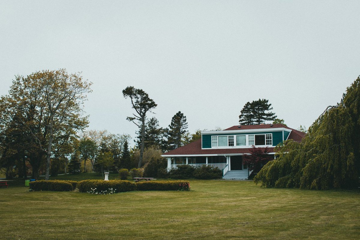House with a long front porch behind a wide, mowed lawn