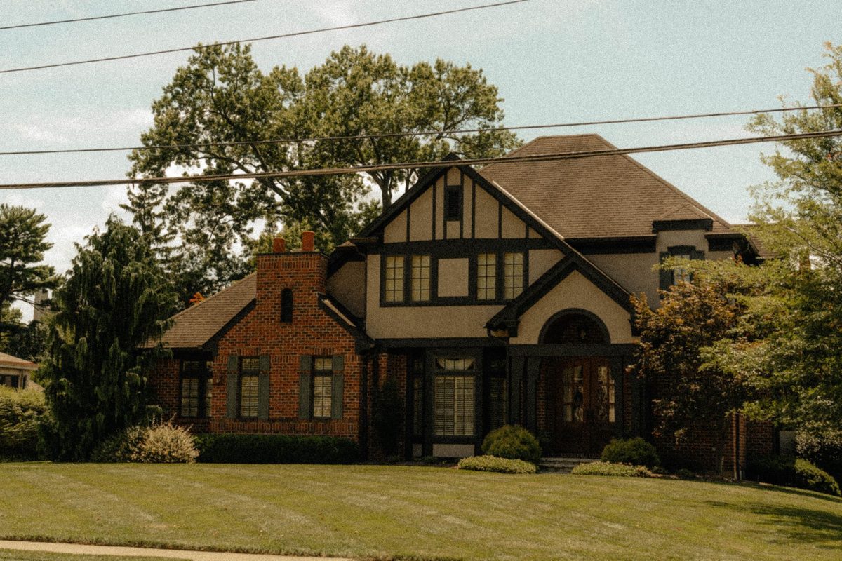 Brick Tudor-style house behind a wide green lawn