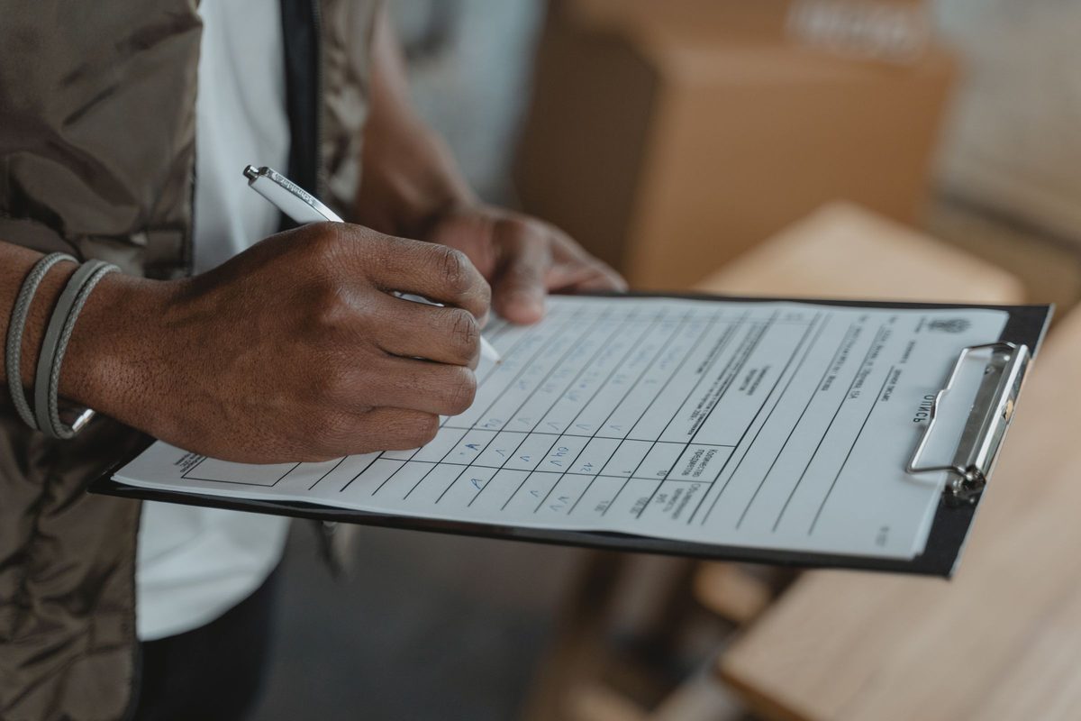 Hands filling in a checklist on a clipboard