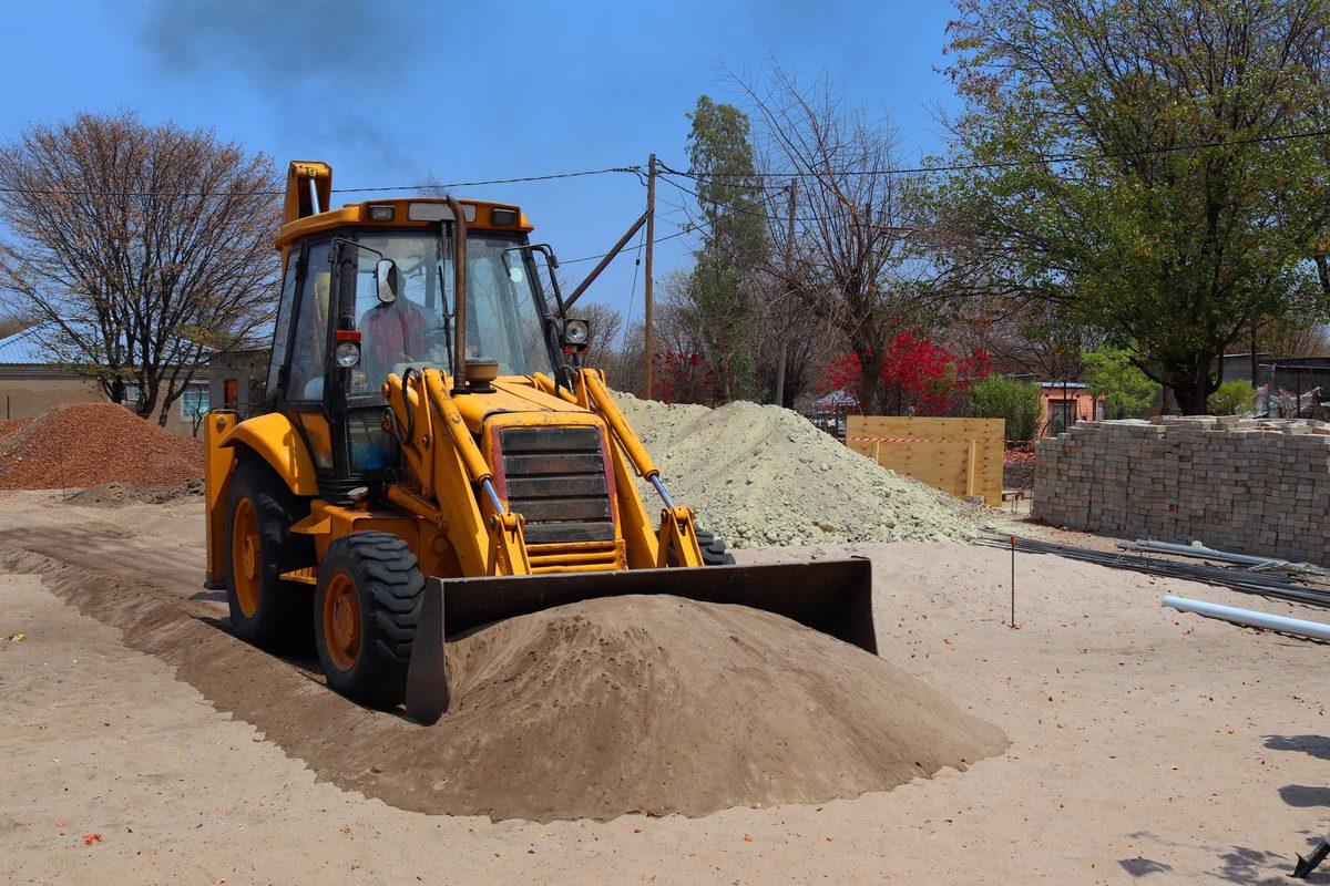 Backhoe loader pushing a pile of sand at a work site